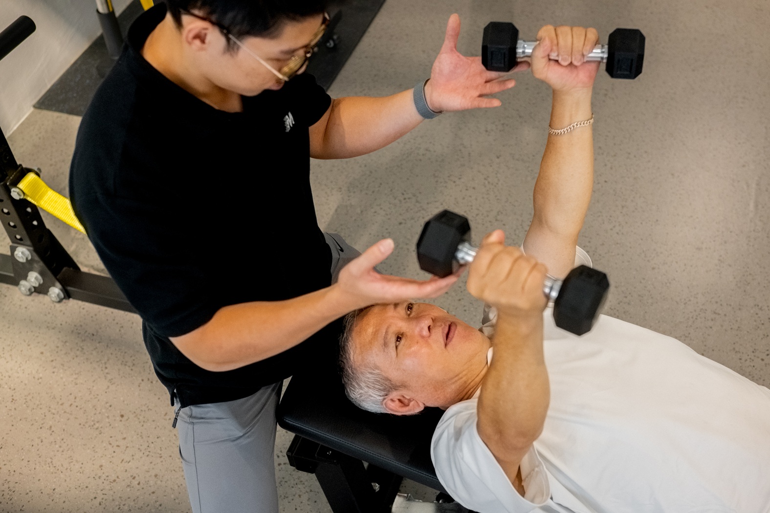 MOVE coach guiding an older client through a dumbbell chest press
