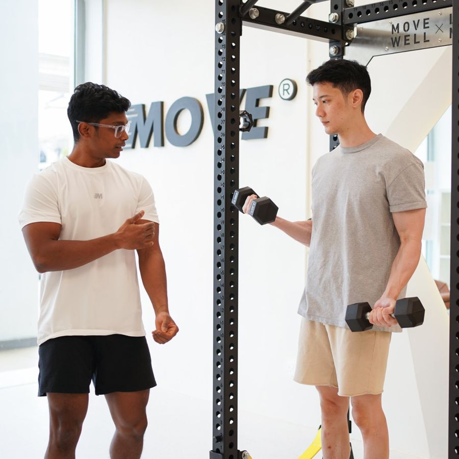 A coach guiding a client through a dumbbell exercise