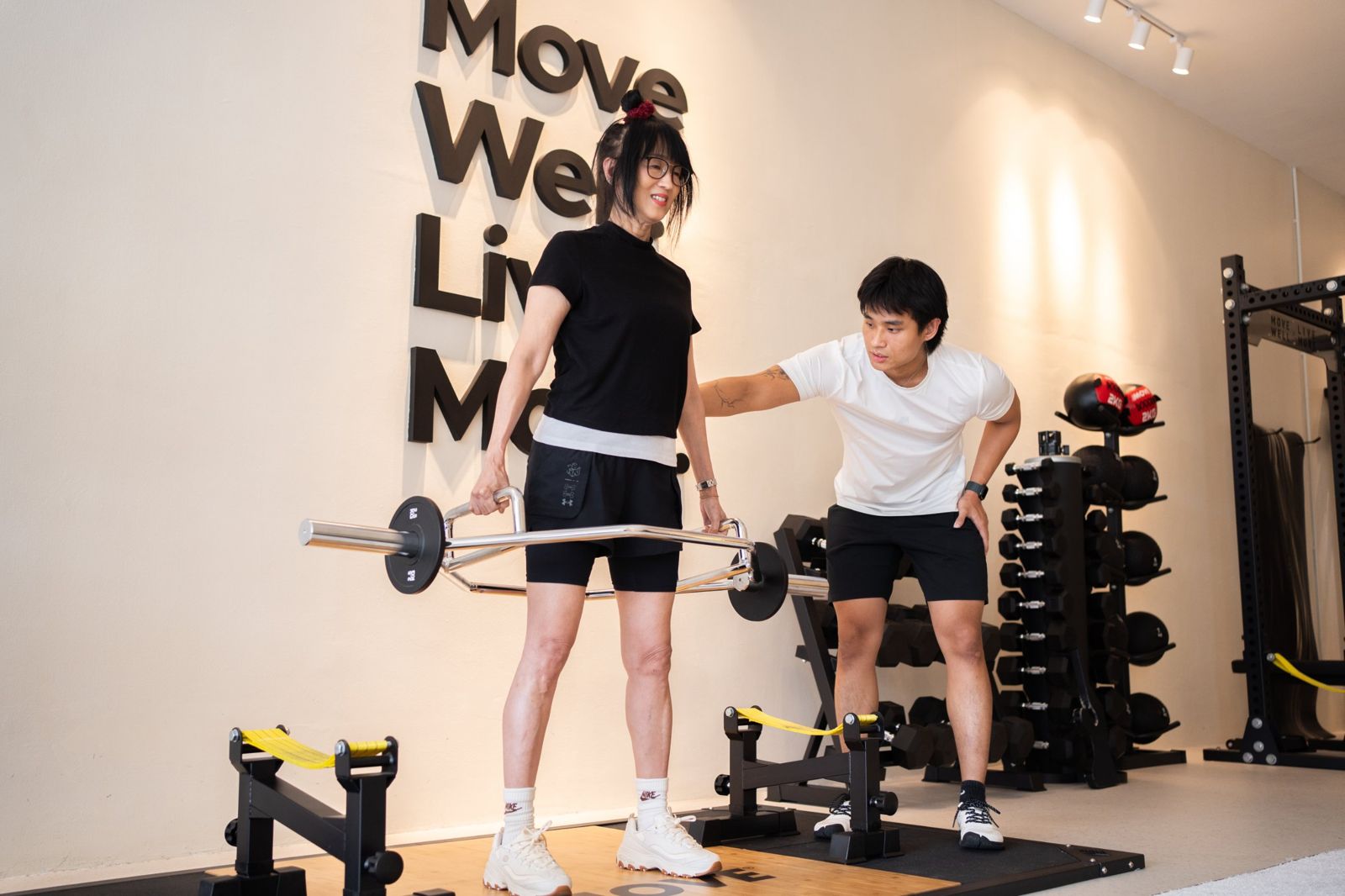 A MOVE coach guiding a client through a trap bar lift in the studio