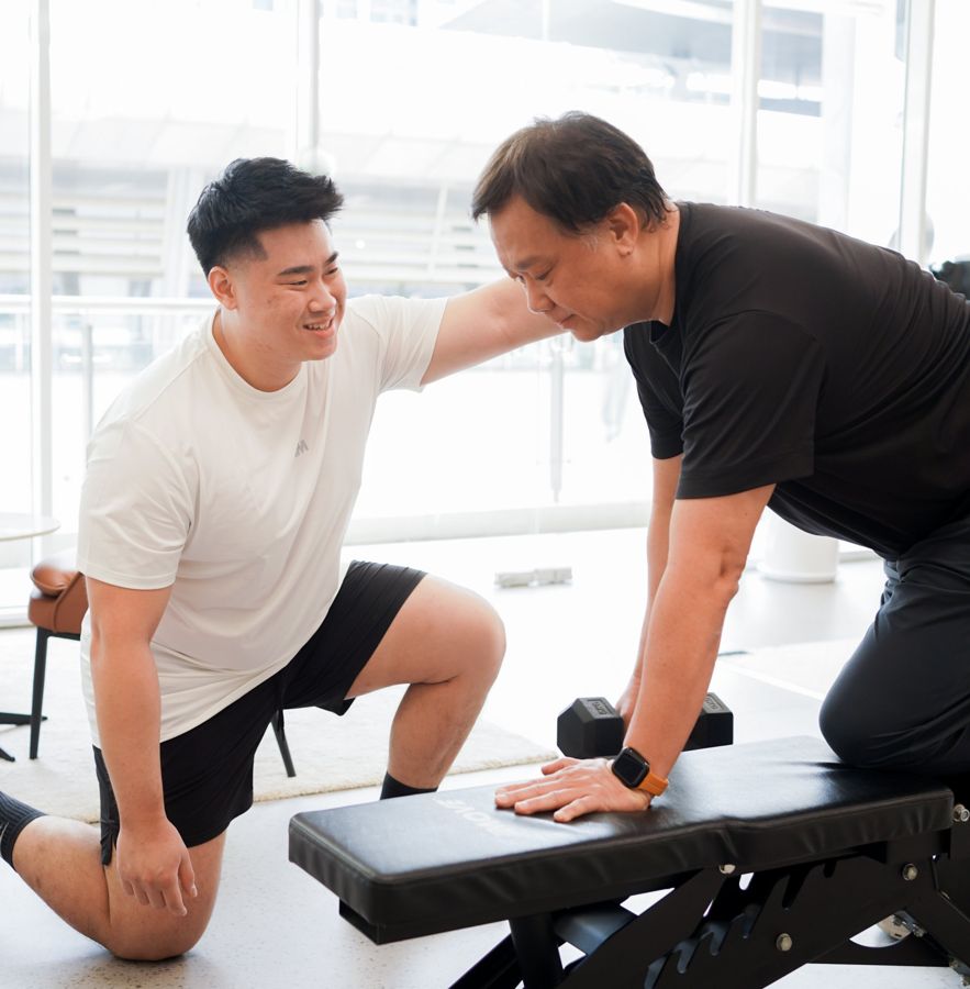 A coach guiding an older client through a single-arm dumbbell row